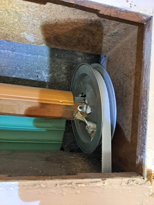 Vecchio rullo in legno con cinghia sfilacciata sulla puleggia – cambio cinghia tapparella a Villanova di Camposampiero